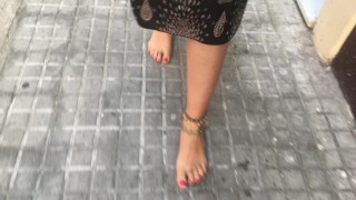 young female hippie is walking barefoot in public street