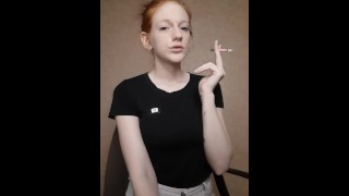 Fille rousse fume une cigarette, les cheveux sont réunis dans un chignon